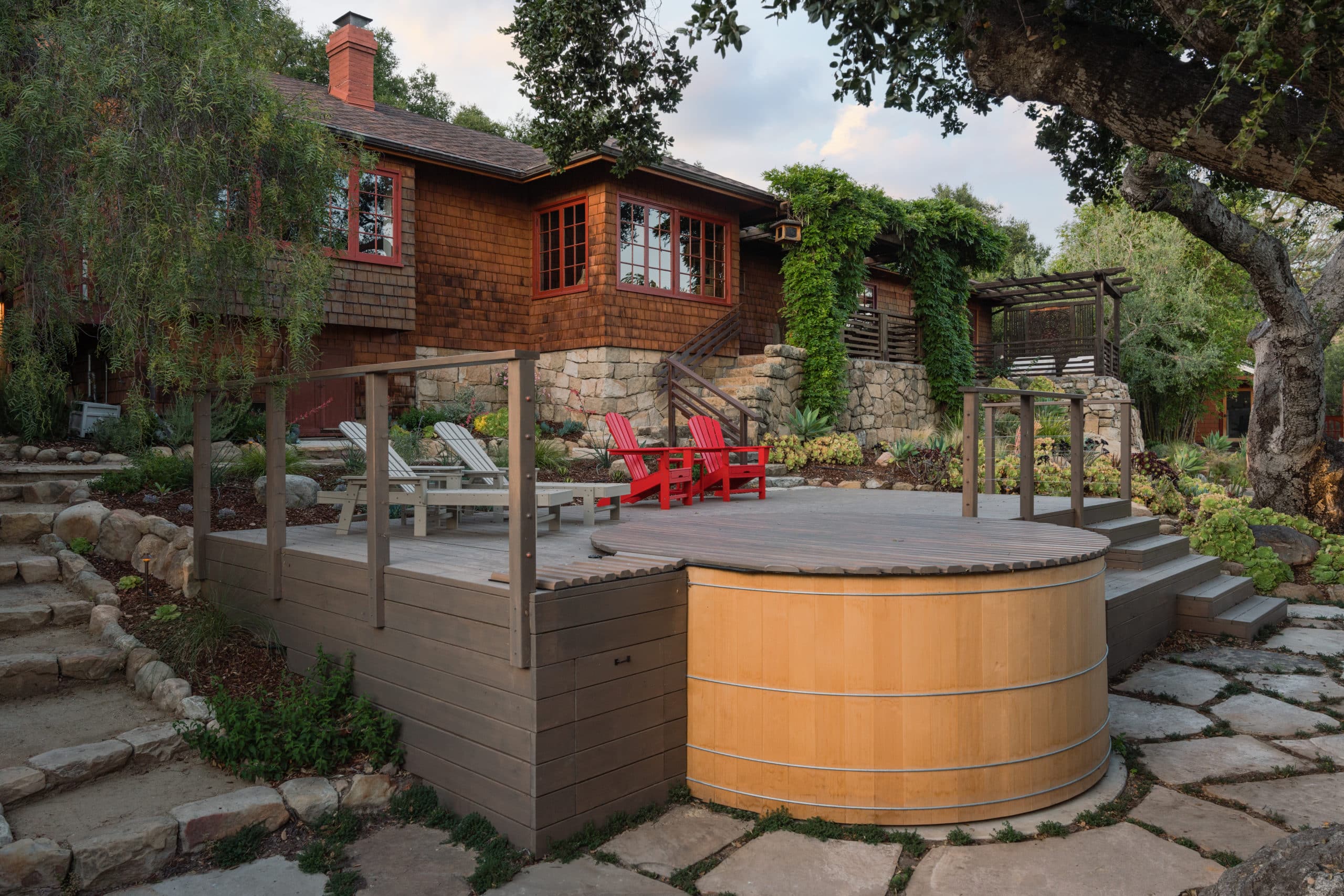 Finished yard with hot tub, red Adirondack chairs, pavers and lush plantings